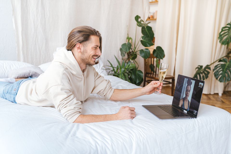 A man smiling on a video call in a cozy bedroom