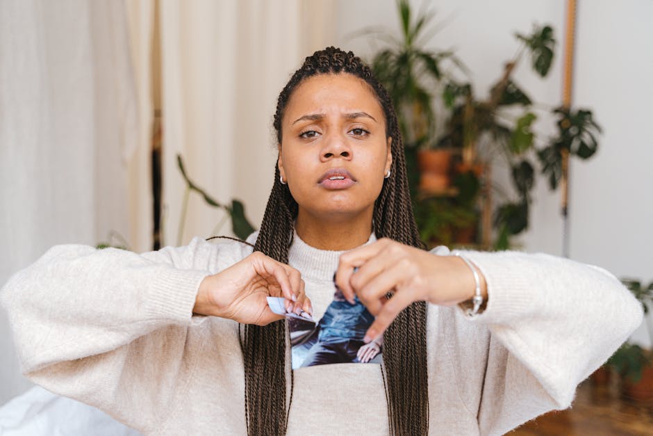A young woman expressing emotion by tearing a photograph in a cozy indoor setting.