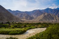 Green Grass Field Near River and Mountains