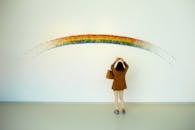 一名妇女在室内驻足，欣赏着色彩缤纷的彩虹艺术装置