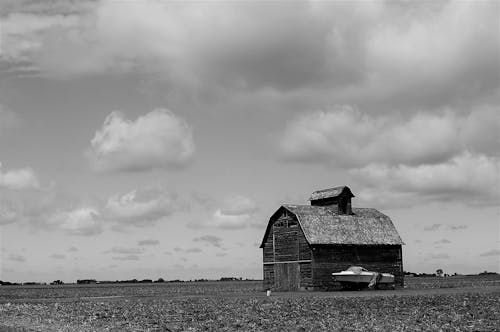 A Grayscale Photo of Barn House with a White Speed Boat