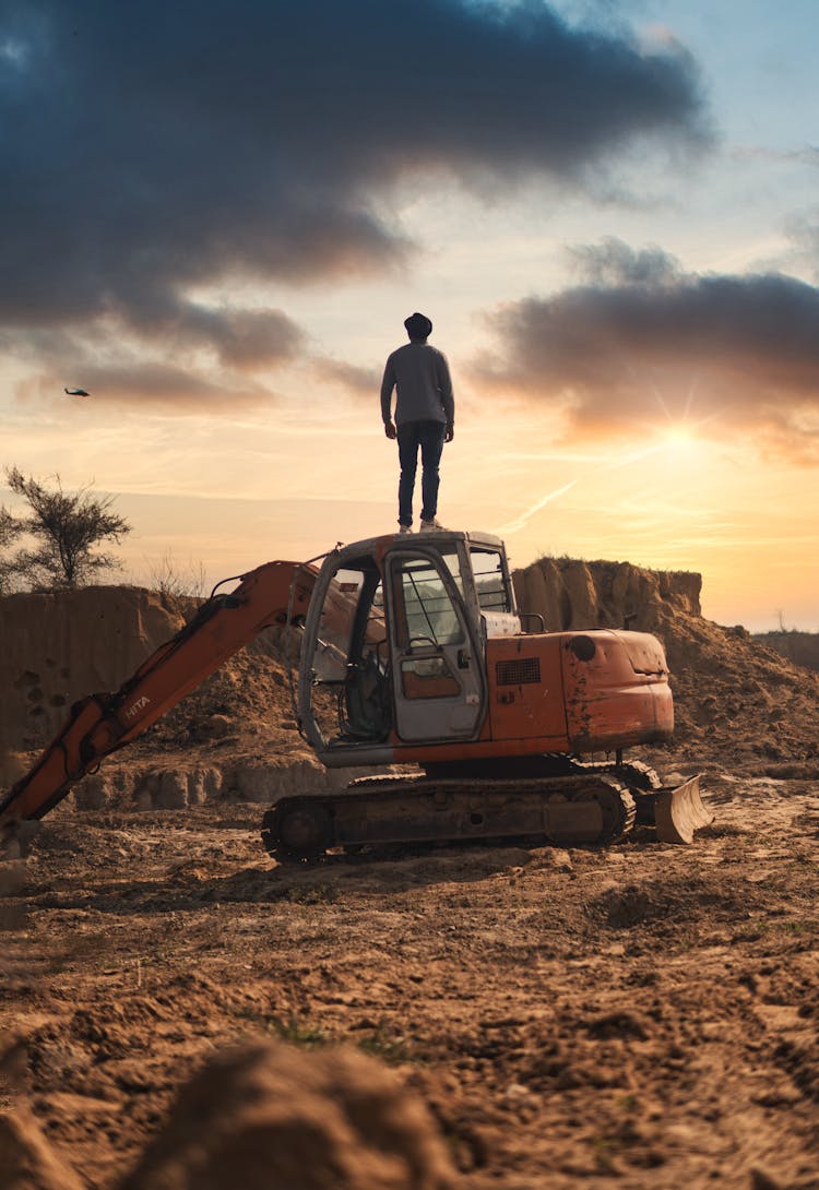 Man Standing On A Backhoe