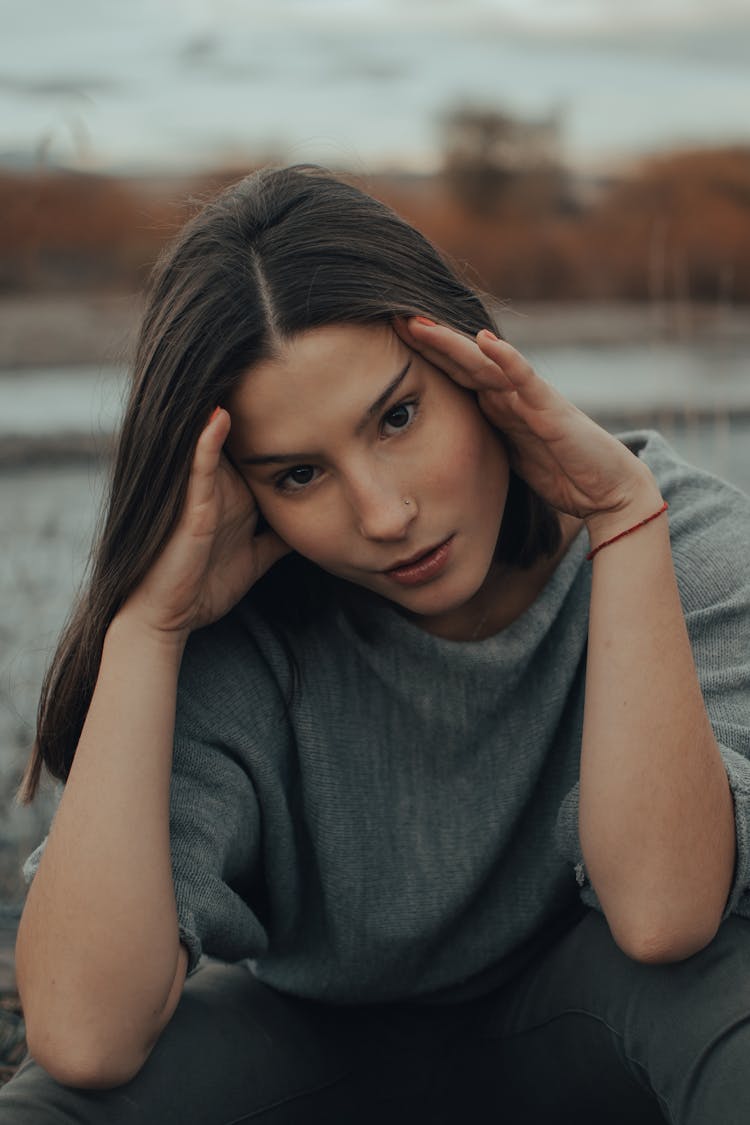 A Young Woman In Gray Shirt Stretching Her Face