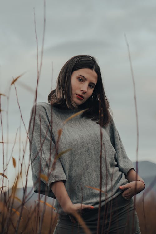 Woman in Gray Shirt Standing on Brown Grass Field