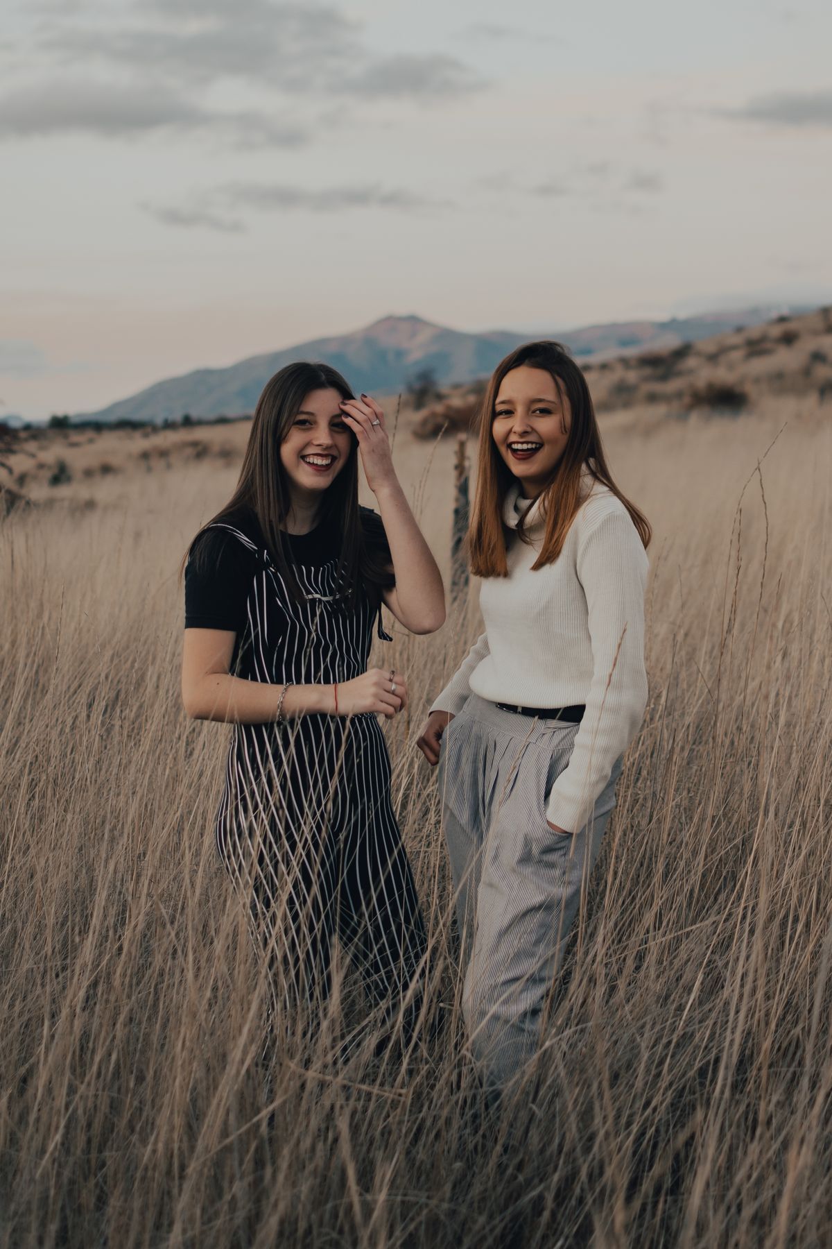 Two members laughing together in a grass field at dusk — photo by Gaspar Zaldo on Pexels