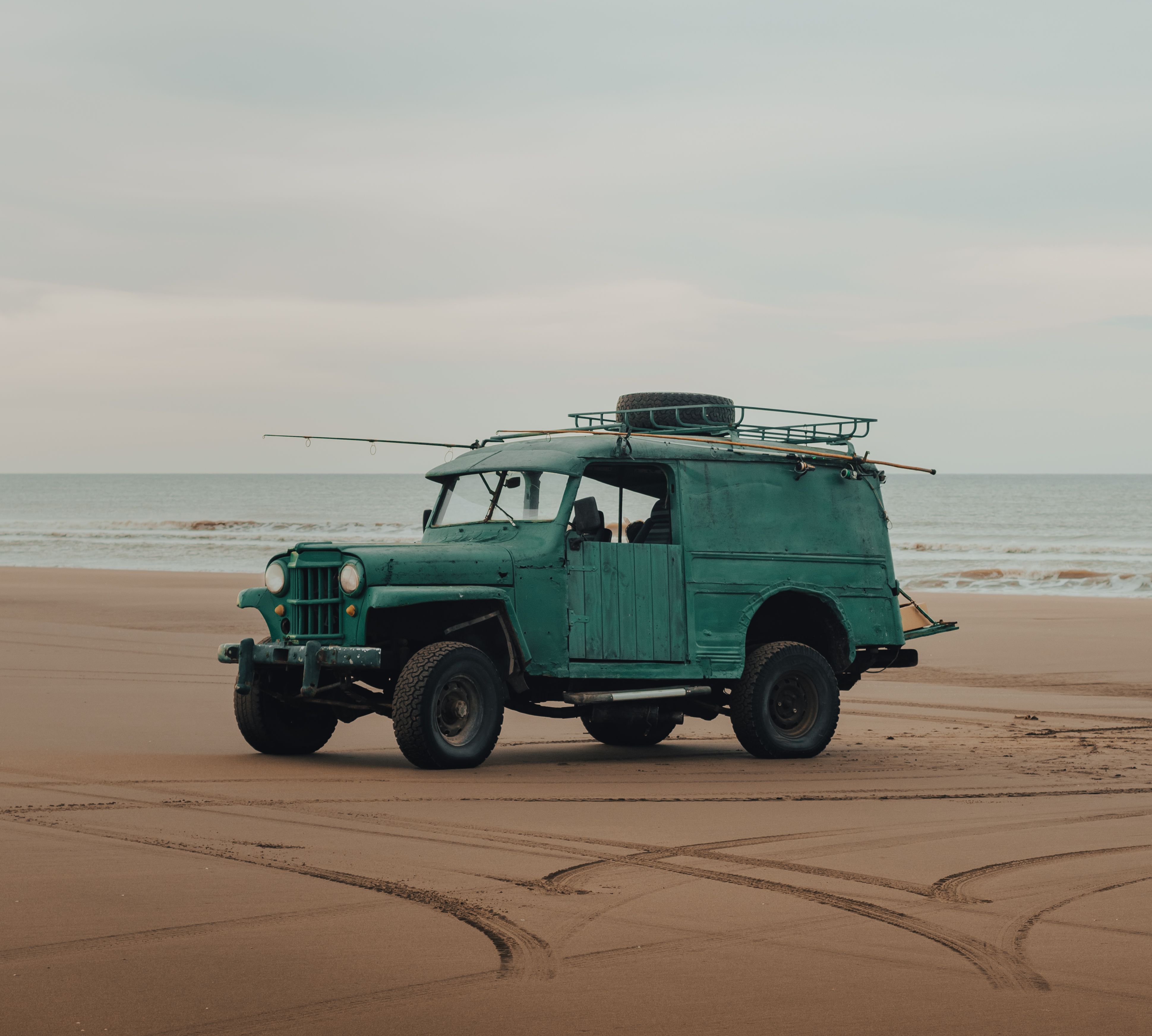 A Vehicle Parked on Sand Near the Seashore · Free Stock Photo