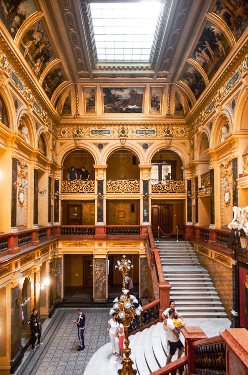 People in hall of Lviv Theater of Opera and Ballet interior located in Ukraine in Lviv with stone stairs and railings near ornamental elements and arched passages