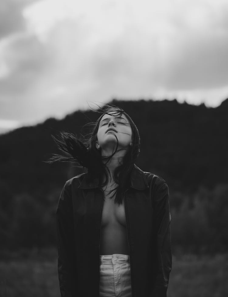 Thoughtful Young Woman Standing In Highland With Closed Eyes Under Overcast Sy