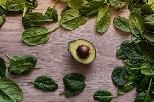 Free Half Sliced Avocado and Green Leaves on Wooden Table  Stock Photo