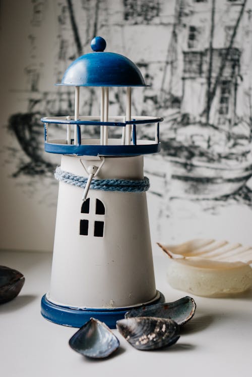 Composition of toy lighthouse and scattered seashells on table