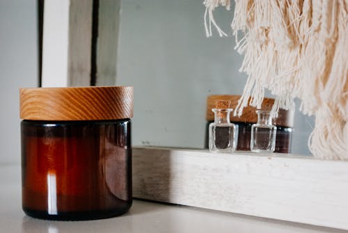 Perfume bottle and skin care product jar placed near mirror