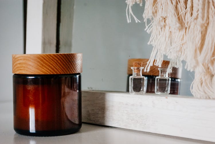 Perfume Bottle And Skin Care Product Jar Placed Near Mirror