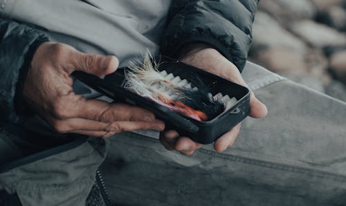A Person Holding Black Box with Fishing Feather Lure