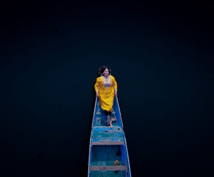 Drone shot of a woman in a yellow dress lying on a boat in Srinagar.
