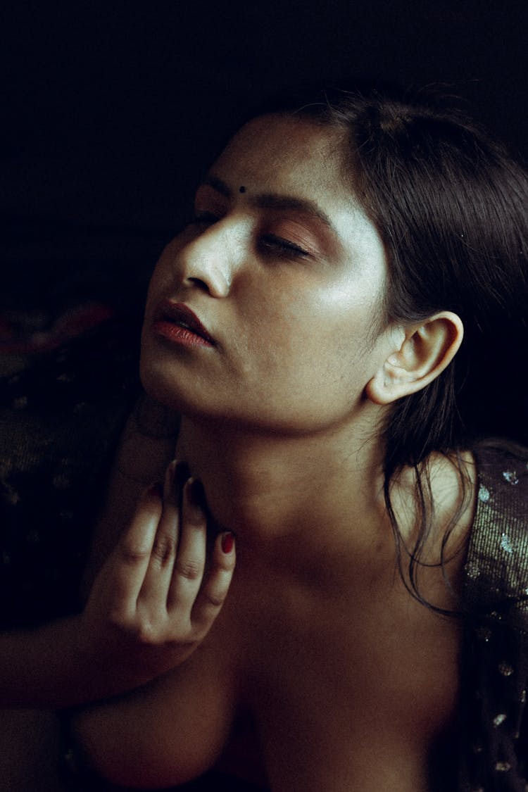 A Woman With Eyes Closed Touching Her Neck