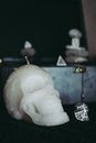 Skull shaped candle with dices and various stones placed on table during Halloween celebration