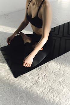 Person sitting in a yoga pose on a mat, embracing peace and mindfulness indoors.