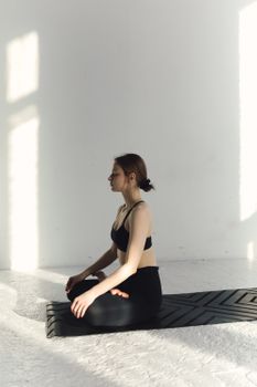 Adult woman meditating on a yoga mat indoors, embodying calm and mindfulness.