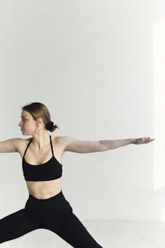 A woman performs a yoga pose in a minimalist indoor setting, emphasizing fitness and healthy living.