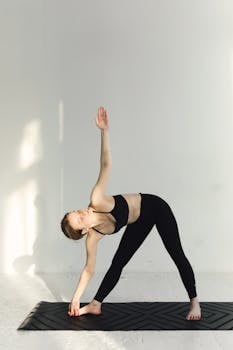Woman in sportswear performing a yoga pose indoors, showcasing healthy lifestyle and flexibility.