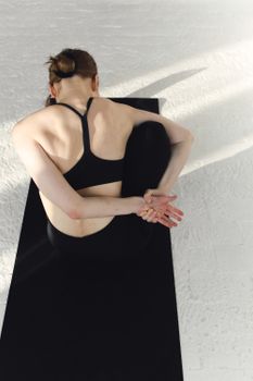 Back view of a woman practicing a yoga pose indoors, promoting a healthy lifestyle.