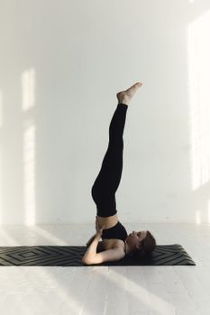 A woman performs a yoga headstand indoors, capturing a moment of balance and mindfulness.