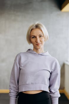 Confident young woman wearing pastel hoodie, smiling indoors.
