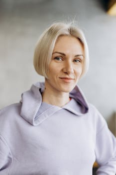 Portrait of a confident woman in casual active wear indoors, smiling slightly.