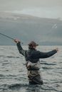 Man in Black Jacket and Brown Pants Holding Black Fishing Rod