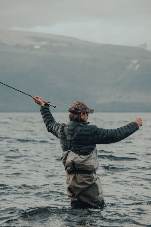 Free An adult man in waders fly fishing in a serene mountain lake. Stock Photo