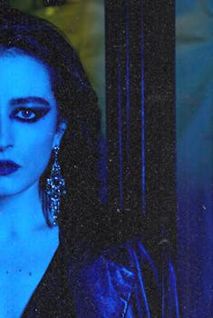 Crop extravagant female with dark hair and makeup looking at camera in blue ultraviolet light