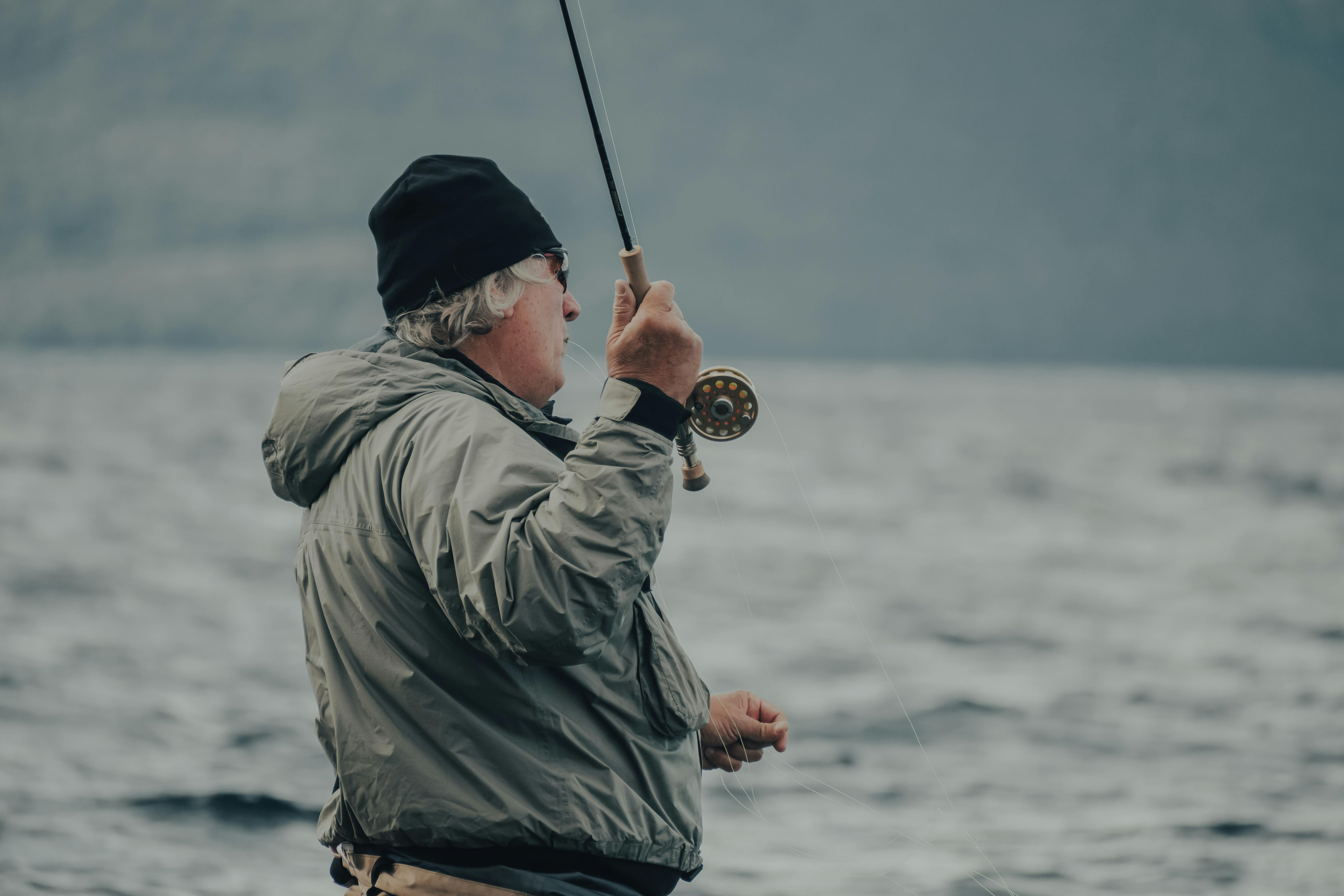 Senior man enjoying fly fishing in the serene outdoor waterscape.