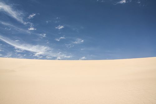 Free Wide angle of smooth sand dune in endless desert valley against beautiful blue sky under bright sunlight Stock Photo