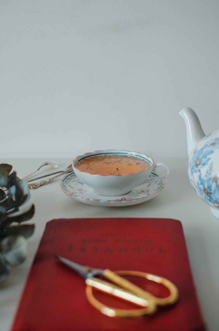 Cup Of Tea Near Book And Scissors At Table