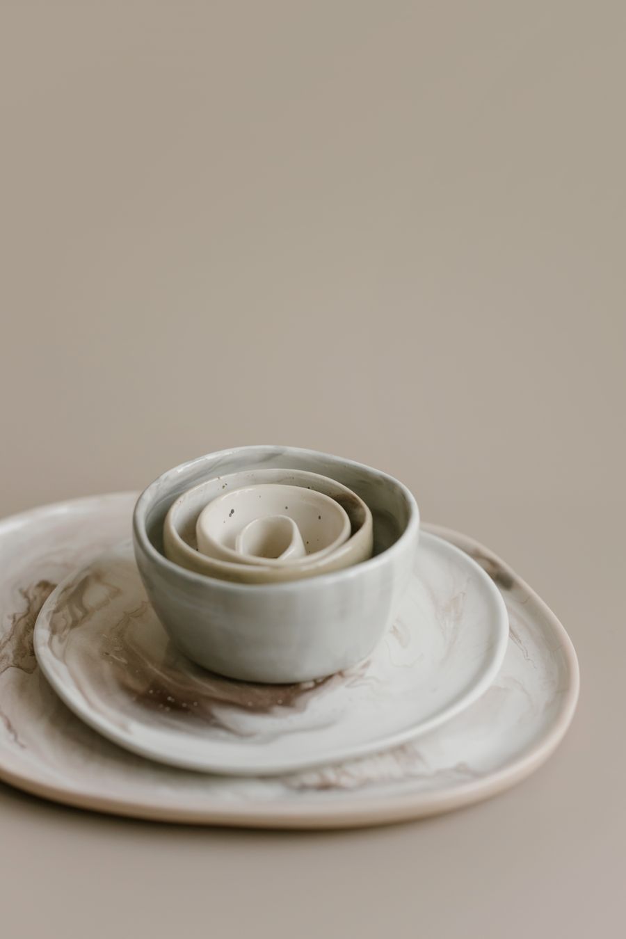 White porcelain-slip nesting bowls stacked on a marbled plate