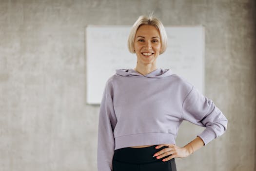 Happy woman in fitness wear poses confidently indoors, promoting healthy lifestyle and exercise.