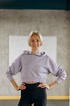 Confident woman in sportswear smiling indoors at the gym, embodying health and fitness.