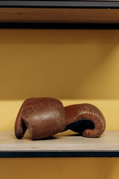 Close-up of a vintage brown leather boxing glove displayed on a shelf.