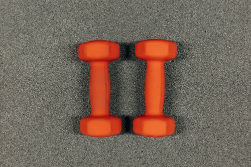 Pair Of Orange Dumbbells On Gray Surface