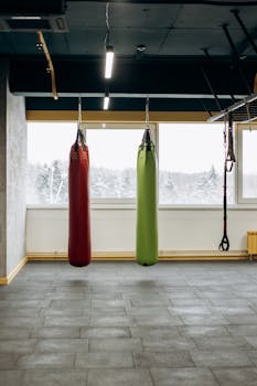 Spacious gym interior featuring red and green punching bags, ideal for fitness activities.
