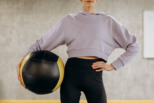 Confident woman in gym gear holding a medicine ball, ready for fitness training.