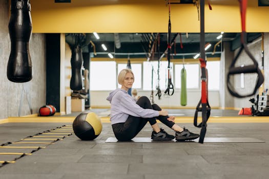 A focused woman working out in a modern gym setting with exercise equipment.