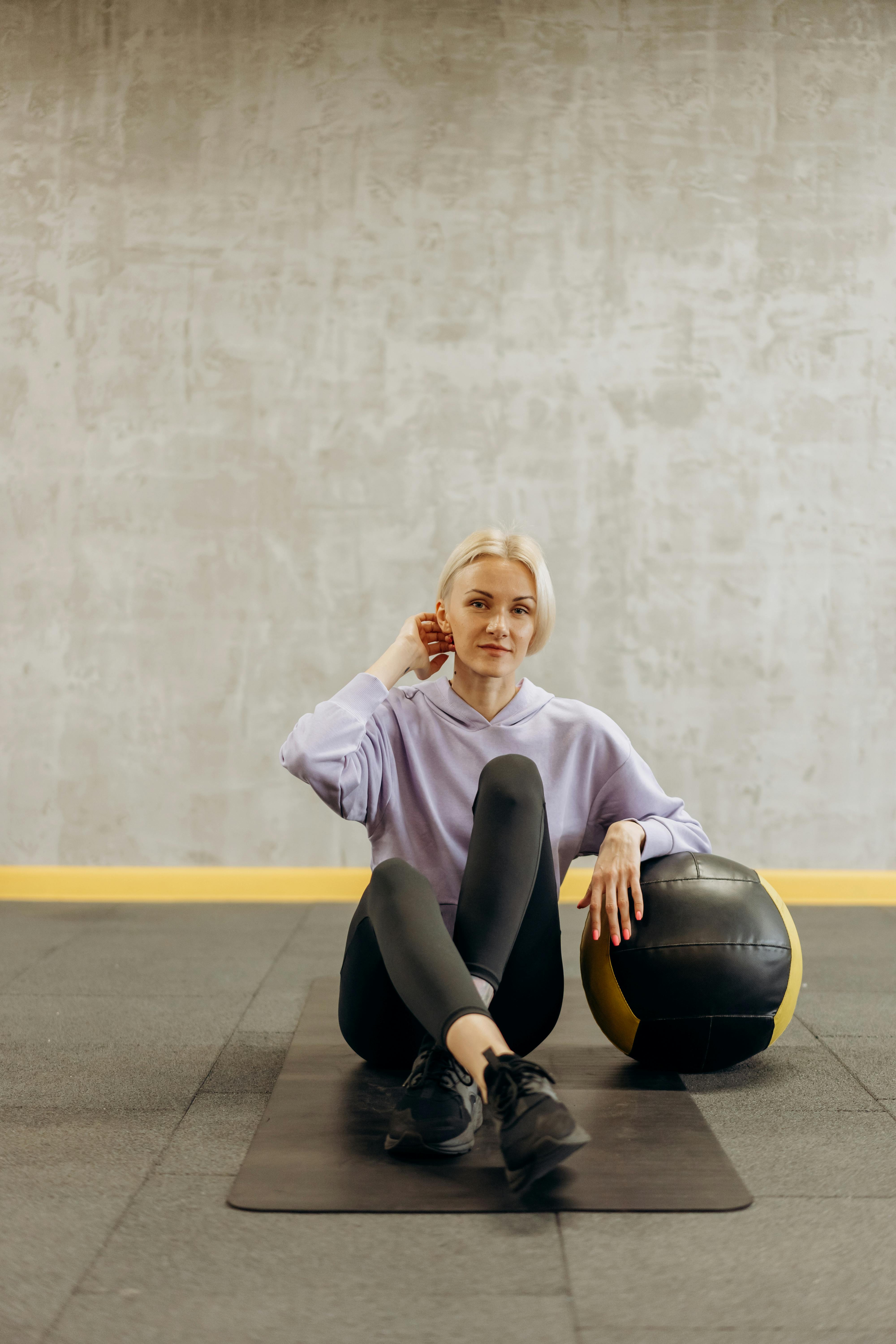 woman sitting on a mat with a ball