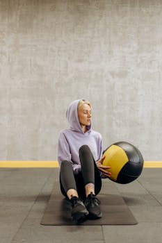 Woman in activewear exercising indoors with a medicine ball, promoting healthy lifestyle and fitness.