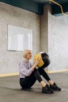 A focused woman performs a fitness routine indoors using a medicine ball.