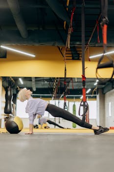 A woman performs a stretching exercise in a contemporary gym, promoting fitness and wellness.