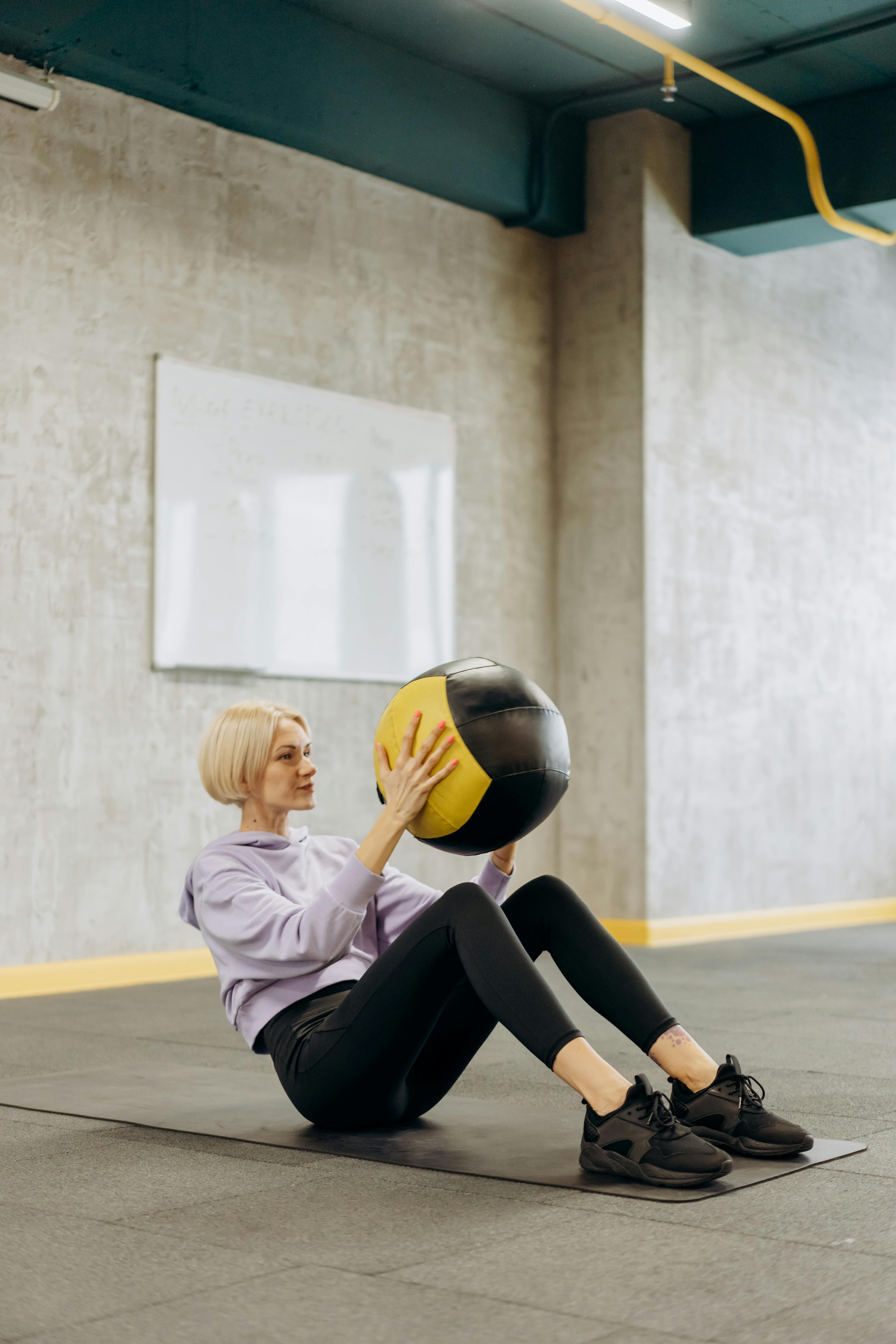 woman sitting on a mat with a ball