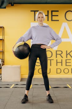 Woman holding a medicine ball in a gym, showcasing strength and focus.