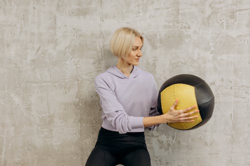 Free Woman Standing Near The Wall Holding A Ball Stock Photo