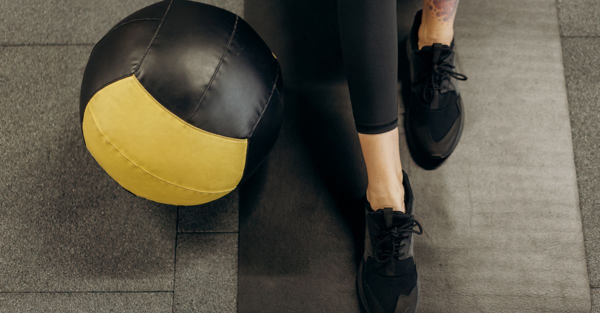 person foam rolling leg with pained expression on gym floor